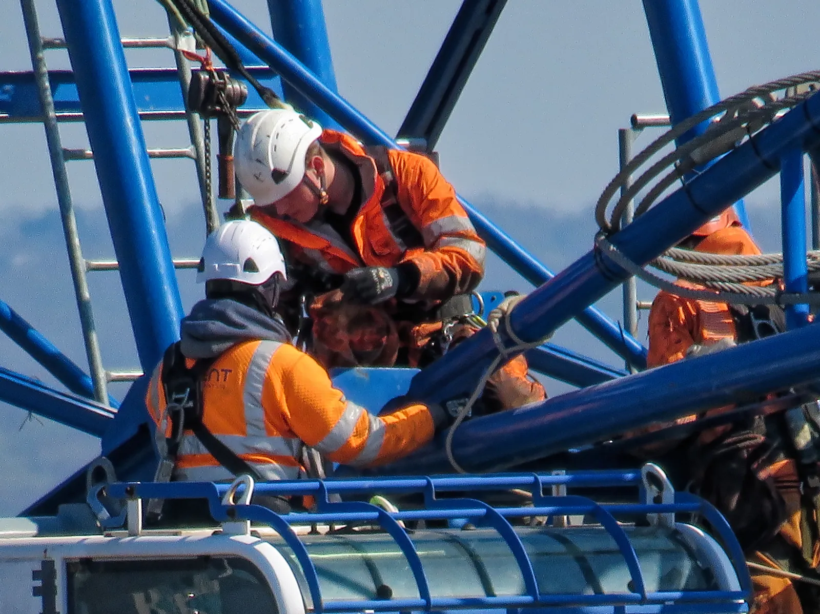Two workers in harnesses and hard hats on a steel structure